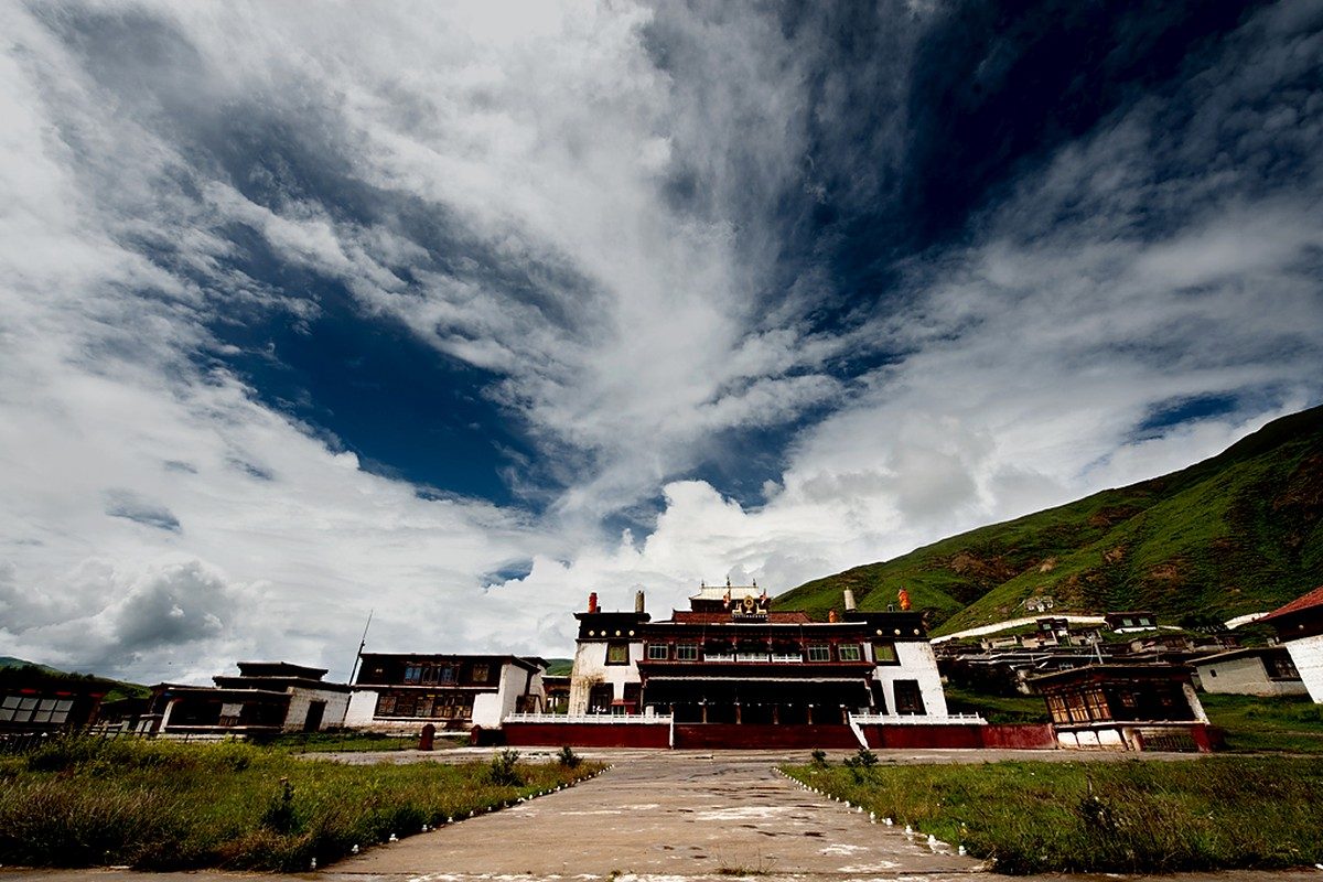 Kasa monastery: white buildings with red trim on a hillside above the lake