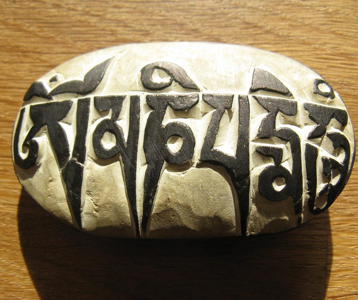 A single flat stone with the six-syllable mantra carved deep into it and painted black