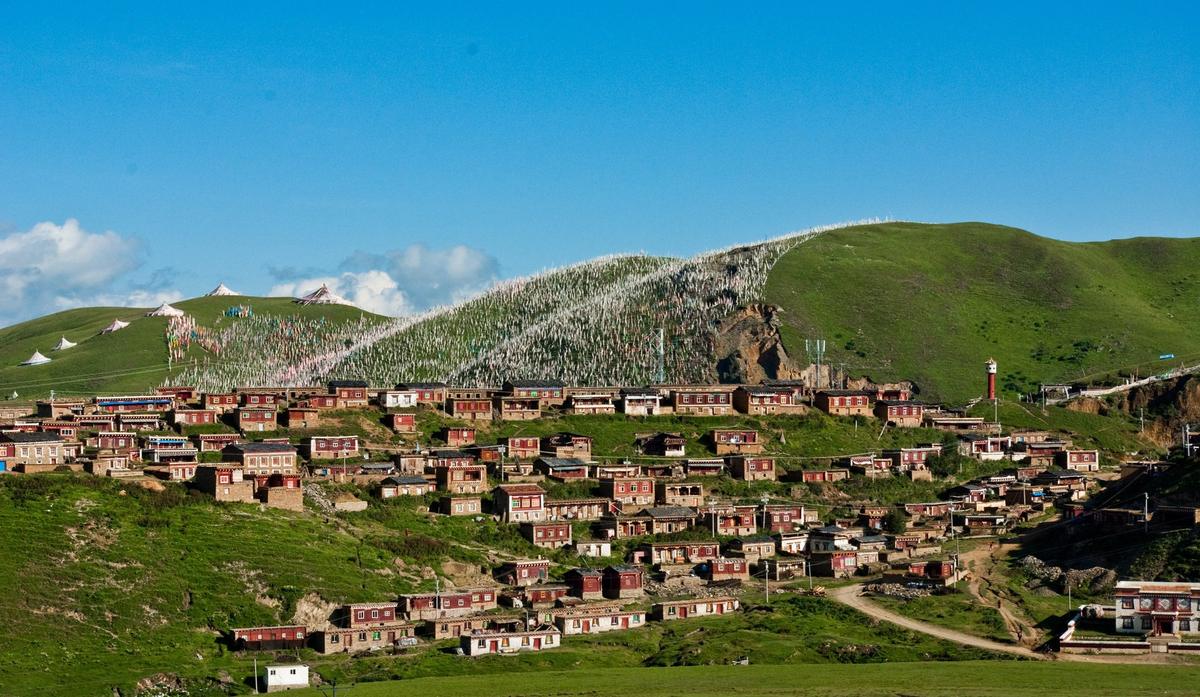 Tagong: the monastery and the monks' houses below a hill covered in prayer flags