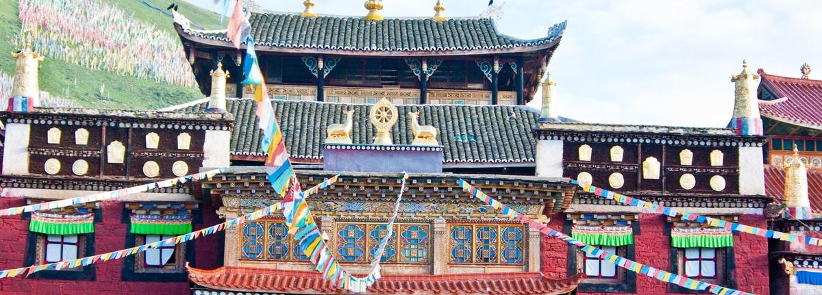 The main hall of Tagong monastery: red walls, a Chinese tiled roof, gilded finials and prayer flags