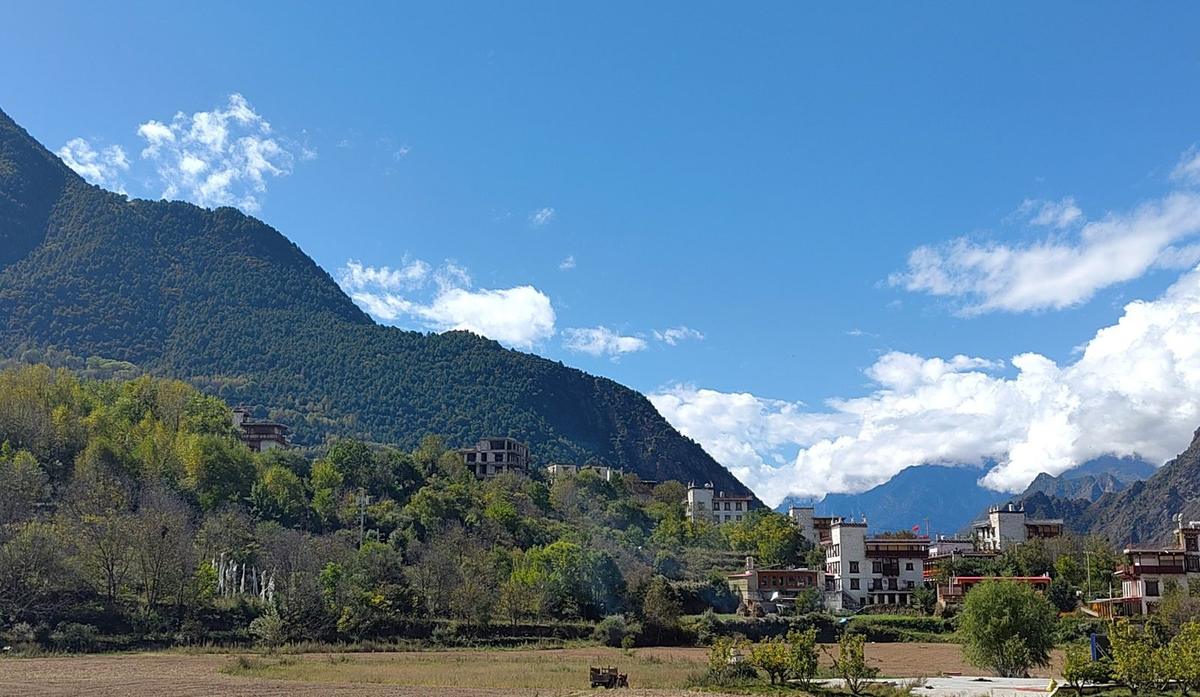 Zhonglu: white houses and a stone tower on a slope above the valley floor